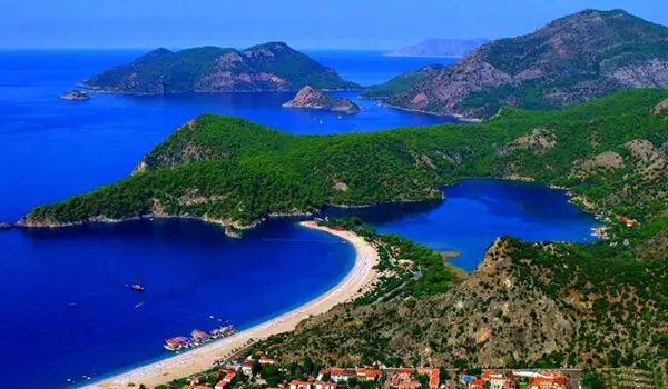 Fethiye'nin dünyaca ünlü Ölüdeniz Lagünü'nü kuşbakışı betimleyen bu fotoğraf, yemyeşil ormanlarla kaplı dağların ve masmavi denizin kucaklaştığı, kıyıdaki beyaz kumlu plajı ve birkaç teknenin görüldüğü bu dingin destinasyonu doğaseverlere harika bir seçenek olarak sunuyor.