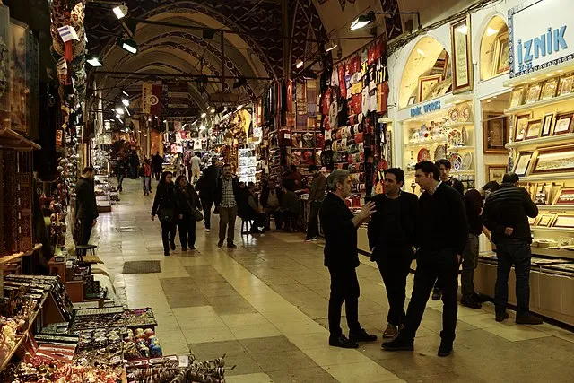 İstanbul Kapalıçarşı’nın içinde yürüyen insanlar ve geleneksel hediyelik eşyalarla dolu dükkânlar.
