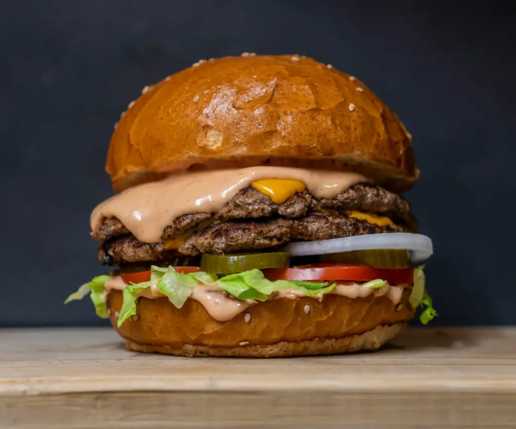 Domates, turşu, soğan ve bol sosla hazırlanan iki katlı dev hamburger yakın çekim.