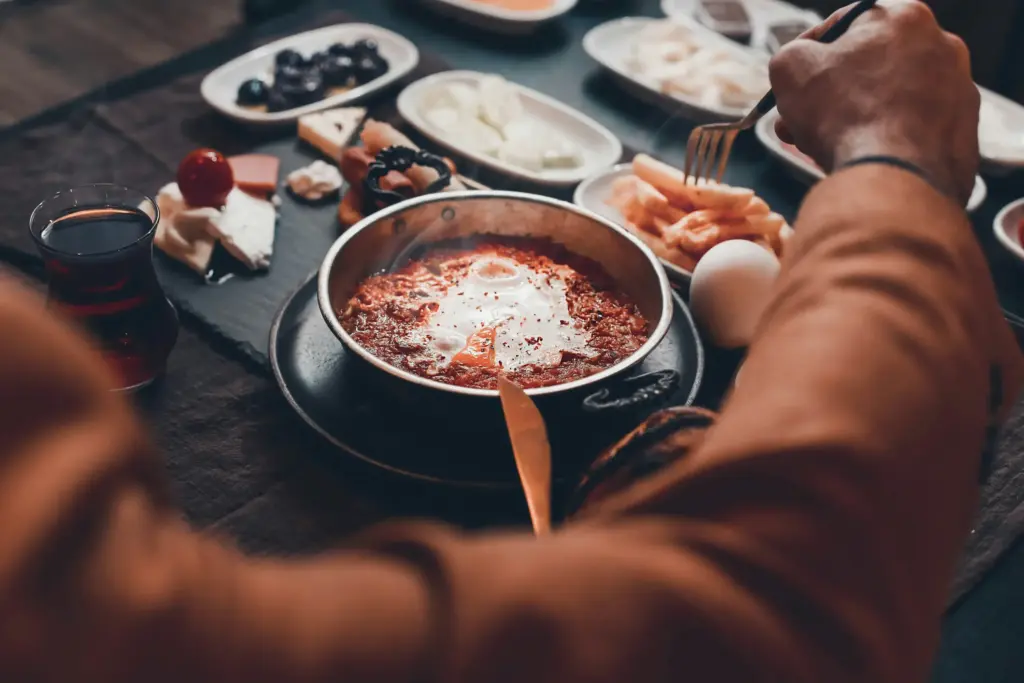 Masada yer alan zengin Türk kahvaltısı tabağı ve közde pişmiş menemen tavası.