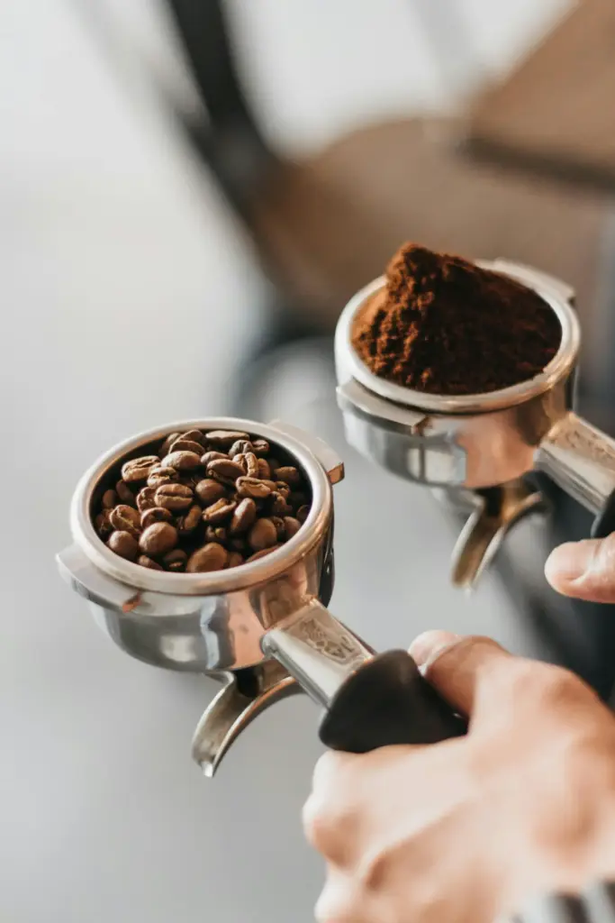 Espresso makinesi portafiltrelerinde kahve çekirdekleri ve taze öğütülmüş kahve.