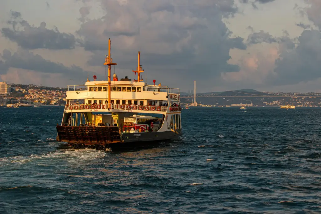 İstanbul Boğazı’nda gün batımı ışığında ilerleyen yolcu vapuru, şehir ve köprü manzarası eşliğinde.