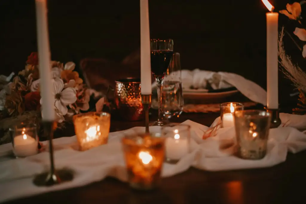 Şarap ve çiçeklerle süslenmiş romantik akşam yemeği masası.