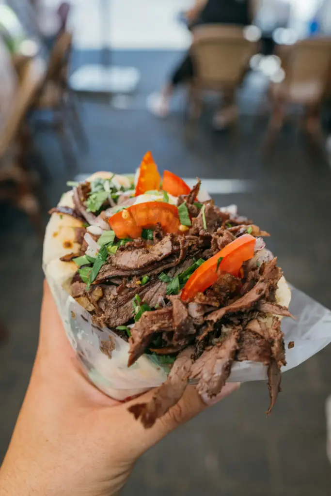 Elde tutulan lavaş içinde bol etli ve domatesli döner dürüm.