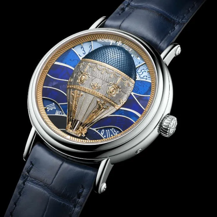 Mavi timsah derisi kayışlı Vacheron Constantin kol saati; kadranında altın ve mine detaylarla işlenmiş üç boyutlu sıcak hava balonu motifi ve dalga desenli lacivert arka plan bulunuyor.