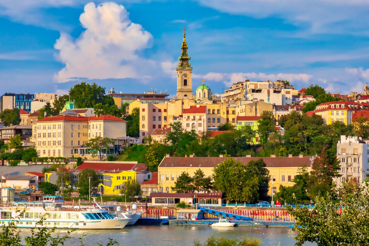 Belgrad'ın tarihi dokusunu ve stratejik konumunu vurgulayan, taş duvarları ve dikkat çekici kuleleriyle Kalemegdan Kalesi'nin geniş bir görüntüsü; rüzgarda dalgalanan Sırbistan bayrağı altında şehrin panoramik manzarasına nazır, yemyeşil ağaçlar ve yapıların çevrelediği bu anıt yapı, kültürel zenginliği simgeliyor.