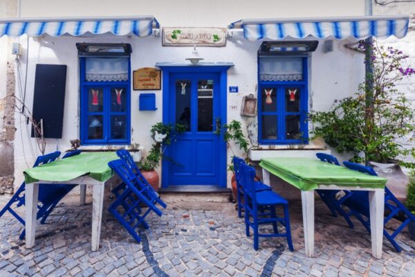 Alaçatı Rehberi'nde Tomris Maravent'in özellikle önerdiği Asma Yaprağı restoranının, üzerinde Asma Yaprağı tabelası bulunan mavi kapı ve pencereleriyle bembeyaz dış cephesi, önündeki Arnavut kaldırımlı sokakta yeşil örtülü masalar ve mavi sandalyelerle özgün bir Alaçatı atmosferi yansıtıyor.