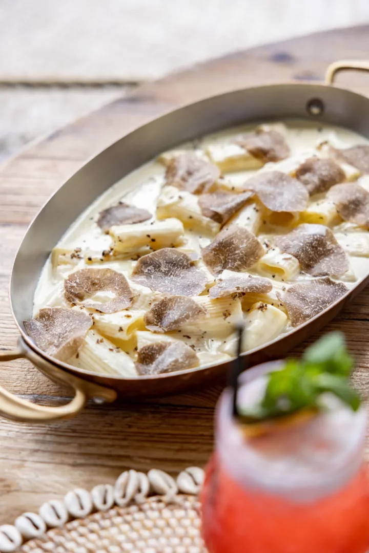Deniz Kurt'un Karayipler'deki favori restoranı Shellona'da servis edilen, kremalı soslu ve bol siyah trüf mantarı dilimleriyle süslenmiş makarnanın, bir mavi yolculuk molasında yaşanabilecek özel lezzet deneyimini vurgulayan şık bir sunumu.