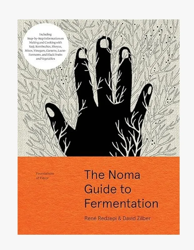 The Noma Guide to Fermentation kitabı kapağı: Siyah bir el illüstrasyonu, dallanma desenleri ve turuncu alt bölüm üzerinde kitap başlığı.