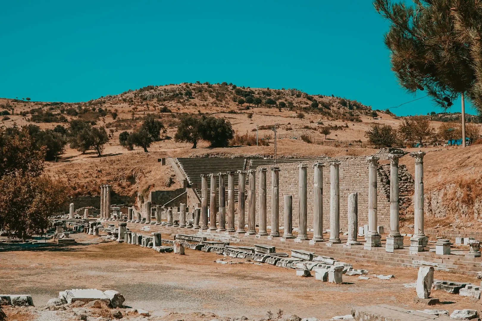 Türkiye'nin birbirinden farklı karakterlerini keşfetme fırsatı sunan bir road trip rotası boyunca UNESCO Dünya Mirası Bergama Antik Kenti'nin kalıntıları arasında, sıralanmış sütunlar ve kademeli oturma alanları, kuru otlarla kaplı tepelerin ve berrak mavi gökyüzünün altında binlerce yıllık tarihi bir atmosfer sunuyor.