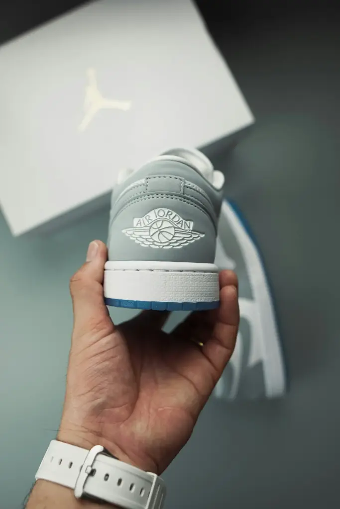 Elde tutulan gri-beyaz Air Jordan spor ayakkabı ve arka planda kutu