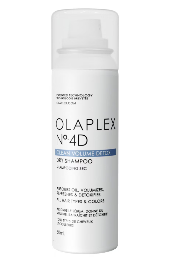 Beyaz arka planda duran, şeffaf kapaklı beyaz silindirik Olaplex N°4D Clean Volume Detox kuru şampuan şişesi, saçlara anında hacim veren ve fazla yağı emerek temiz, ferah bir görünüm kazandıran özelliklerini yansıtıyor.