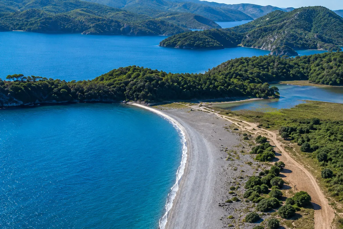Hayvan Dostu Plajlar: Fethiye'de yer alan Karaot Plajı'nın kuşbakışı çekiminde, masmavi berrak suların kavisli çakıllı bir kumsalla yemyeşil ağaçlarla kaplı kara parçasını ayırarak iç lagünle buluştuğu eşsiz doğal güzellik gözler önüne seriliyor.