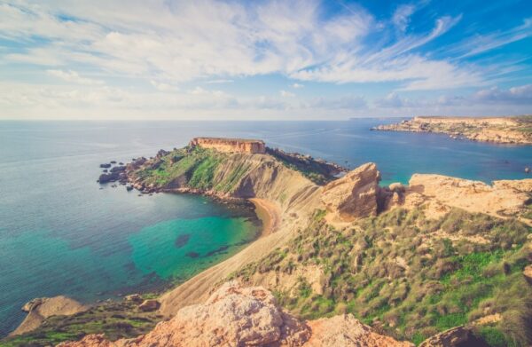 Malta'nın eşsiz doğal güzelliklerinden birini sergileyen bu panoramik fotoğraf, berrak turkuaz sulara sahip kıyı şeridini, yeşilliklerle kaplı sarp kayalıkları ve uzak ufukta Akdeniz'in sonsuz maviliğini gözler önüne seriyor.