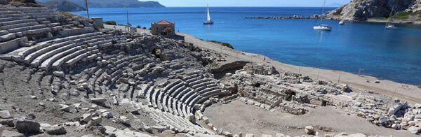 Türkiye’nin eşsiz antik kentlerinden Knidos’ta, parlak mavi denize bakan yamaca yayılmış, taş basamaklı antik tiyatro kalıntıları, koyda demirlemiş beyaz yelkenliler ve uzaktaki tepeler, tarihi bir mirasın doğal güzellikle buluştuğu zamansız bir manzara sunuyor.