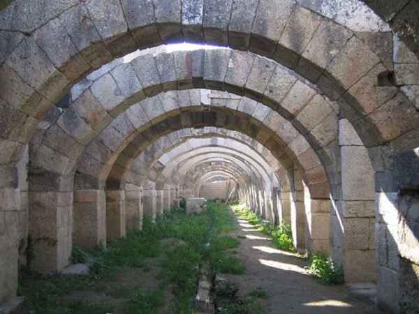 Taş bloklarla örülmüş, uzayıp giden kemerli bir tünel ya da koridor, zeminde toprak ve yeşil otlarla kaplı bir patika ile birlikte, İzmir'deki Smyrna Agorası'nın, antik çağda çarşı olarak kullanılmış katmanlarından birini sergileyen büyüleyici bir Antik Kent kalıntısı.