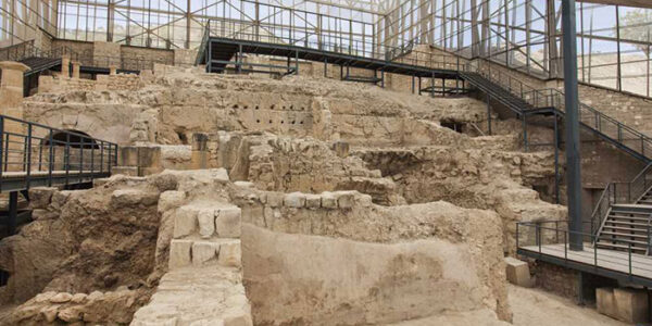 Türkiye’nin zengin antik kentleri arasında yer alan Zeugma Antik Kenti’nden, yıllar süren kazılarla ortaya çıkarılmış, farklı katmanlarda tarihi yapı kalıntıları ve onları ziyaretçilere sunan modern koruyucu çatı ile metal yürüme yolları içeren geniş bir arkeolojik alan gözleniyor.
