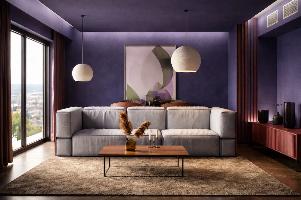 Derin lacivert-mor tonlarda duvarlara sahip modern salon dekorasyonu; gri modüler koltuk, ahşap orta sehpa, yumuşak dokulu halı ve heykelsi sarkıt aydınlatmalarla sofistike ve zamansız bir iç mekân tasarımı.