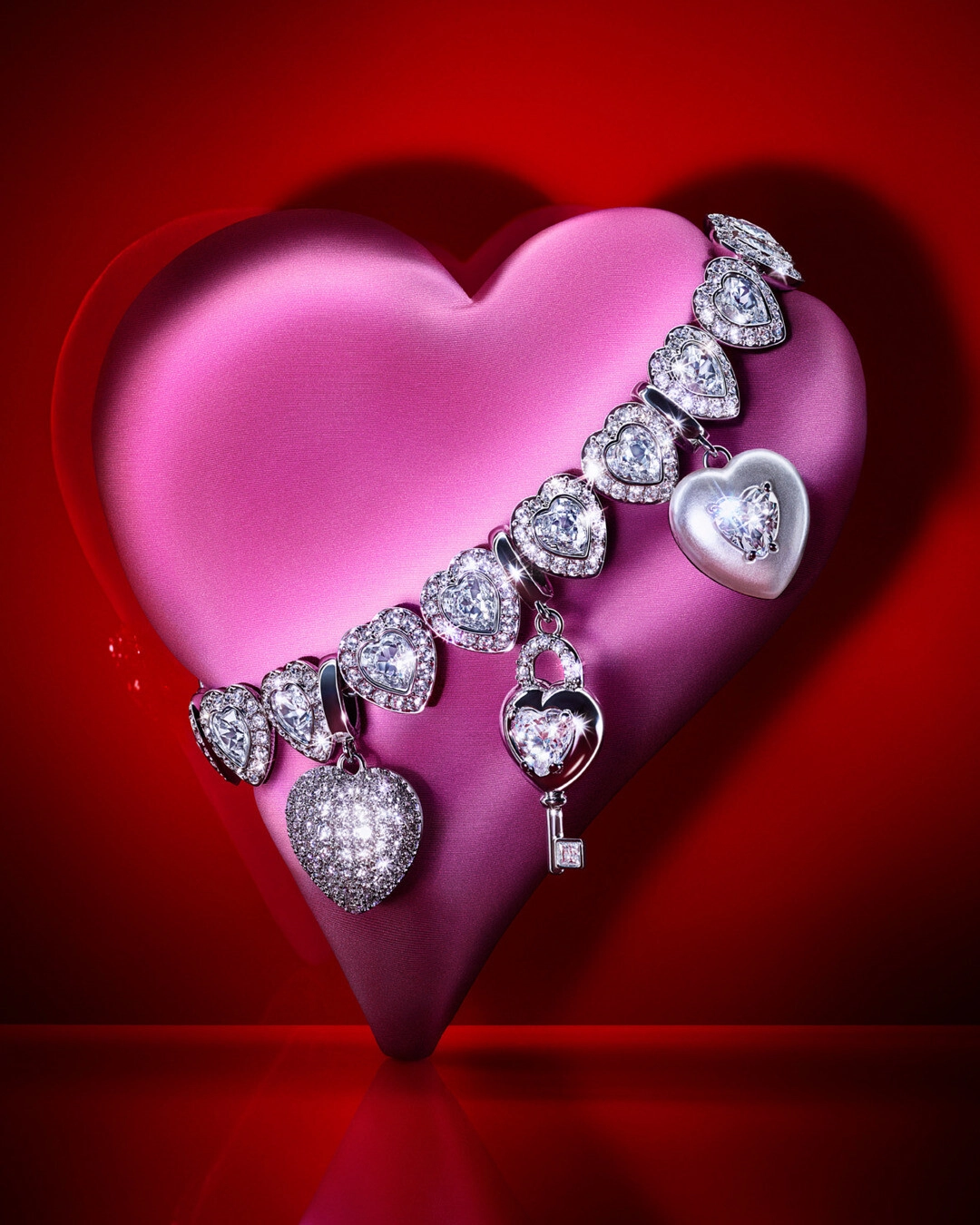 Pembe kalp formunda fonda sergilenen Swarovski kalp motifli pırlanta görünümlü bileklik, Sevgililer Günü için romantik lüks mücevher hediye önerisi kampanya görseli.