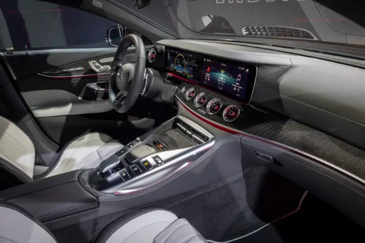 Mercedes-AMG GT 4 Kapı Coupe'nin direksiyon simidi, yüksek çözünürlüklü dijital gösterge paneli, kırmızı detaylı dörtlü havalandırma ızgarası ve geniş orta konsolundaki teknolojik tuş takımıyla lüks ve sportif iç mekanı, zarif karbon fiber kaplamalar ve büyük bilgi eğlence ekranı ile modern bir sürüş deneyimi sunuyor.