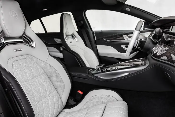Bu görsel, Mercedes-AMG GT 4 Kapı Coupe'nin lüks ve sportif iç mekanını gözler önüne seriyor; beyaz ve siyah deri kaplı, elmas dikiş detaylarına sahip ergonomik spor koltuklar, karbon fiber trimler ve metalik vurgular ile aracın hem performans odaklı hem de dört kişilik konfor sunan yapısını etkileyici biçimde yansıtıyor.