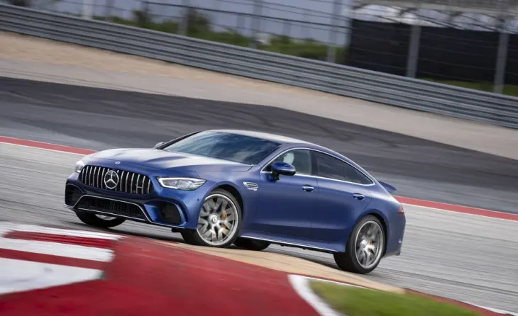 Koyu mavi Mercedes-AMG GT 4 Kapı Coupe, keskin bir virajda dinamik bir şekilde yol alırken aracın sportif performansı ve dört kişilik lüksü bir araya getiren güçlü duruşu yarış pistinde belirginleşiyor.