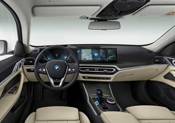 Yeni BMW i4'ün şık iç mekanında, bej renkli deri koltuklar, ahşap görünümlü detaylar ve sürücü odaklı büyük, kavisli dijital ekranıyla modern ve tamamen elektrikli bir sürüş deneyimi sunuluyor.