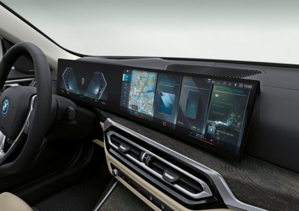 Tamamen Elektrikli Yeni BMW i4 modelinin iç mekanından bir görünümde, sürücü koltuğundan kavisli dijital gösterge paneli ve büyük multimedya ekranı belirgin bir şekilde araç bilgilerini ve navigasyonu yansıtıyor.