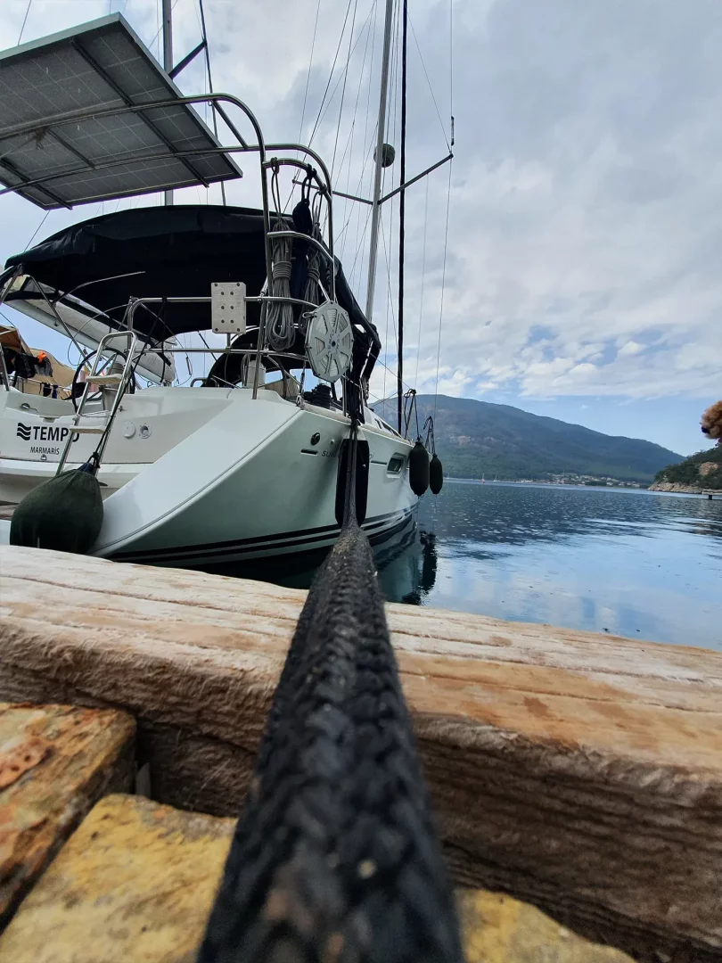 Marmaris'in berrak sularında bir iskeleye bağlı, üzerinde Tempo Marmaris yazan güneş panelli ve yelken donanımlı tekneyi iskeleye bağlayan kalın bir halat, sakin bir yelken deneyimini çağrıştırıyor.