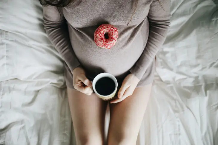 Yatakta uzanmış, karnında pembe renkli ve şekerlemeli bir donut bulunan, ellerinde ise sıcak içecek dolu bir kupa tutan rahatlamış bir anne adayı, doğuma hazırlık sürecinde fiziksel ve psikolojik olarak kendini iyi hissetmenin, küçük keyiflerle dinlenmenin önemini gösteriyor.
