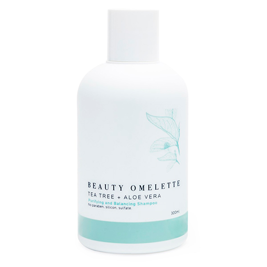 Beyaz zemin üzerinde duran, Beauty Omelette markalı, çay ağacı ve aloe vera içeren, sülfatsız arındırıcı ve dengeleyici formülüyle saçınızı koruyan beyaz bir şampuan şişesi, alt kısmındaki turkuaz detay ve yaprak deseniyle dikkat çekiyor, normal ve yağlı saçlar için ferahlatıcı bir bakım vadediyor.
