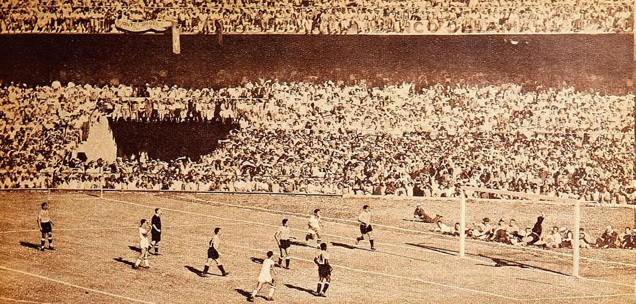 Maracanazo olarak bilinen 1950 Dünya Kupası final maçından, Maracana Stadyumu'nun tıklım tıklım dolu tribünleri ve AVANTE BRASIL pankartı önünde Brezilya ile Uruguaylı futbolcuların mücadele ettiği sepya tonlu tarihi bir kare.
