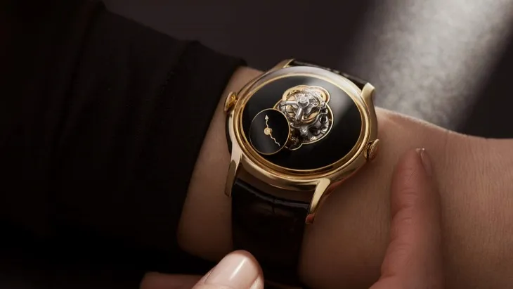 Kollarda sergilenen siyah zeminli ve tourbillon mekanizmalı lüks saat.