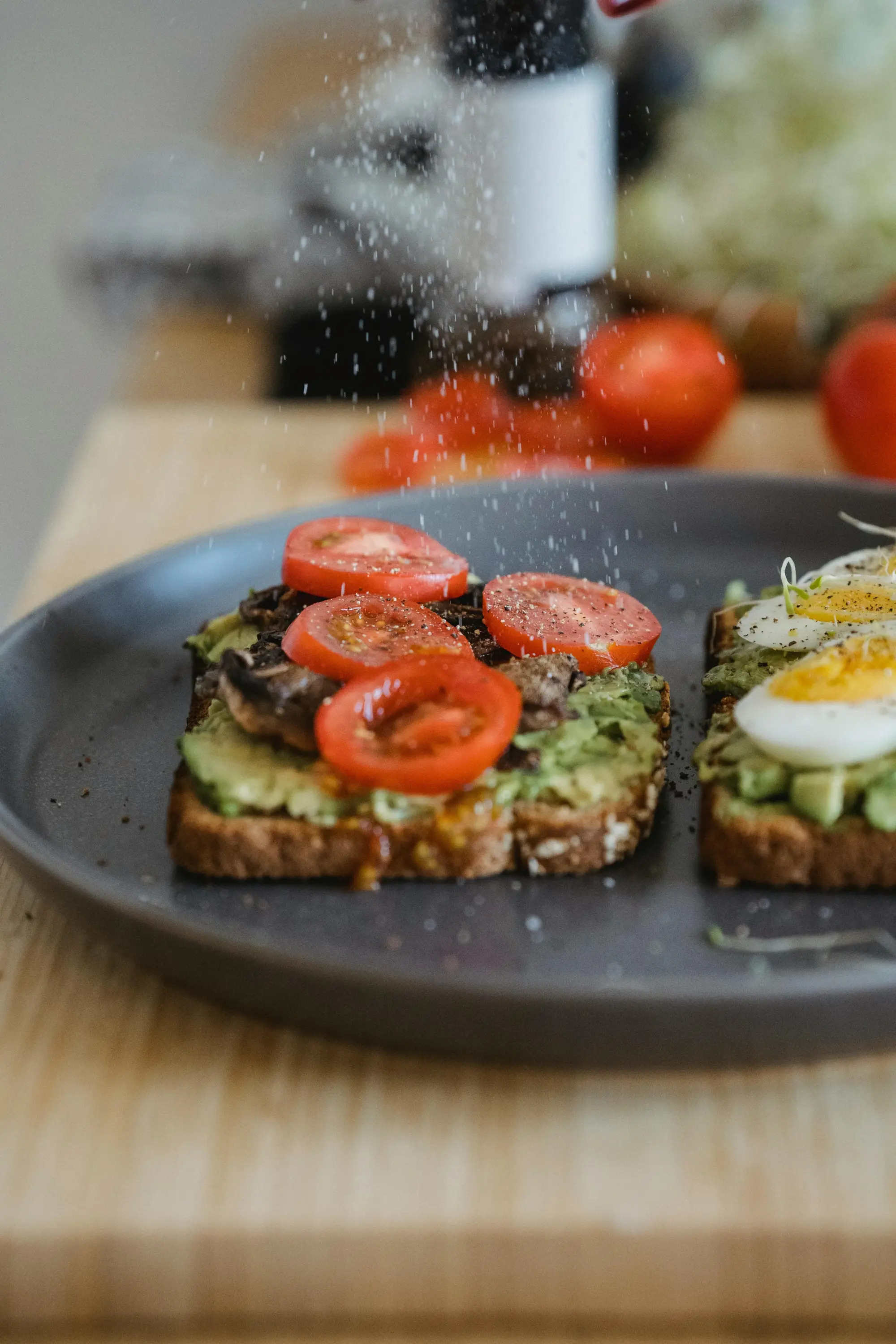 Avokado püresi, domates ve yumurta ile hazırlanmış sağlıklı avokado tost üzerinde baharat serpilirken close-up görünüm