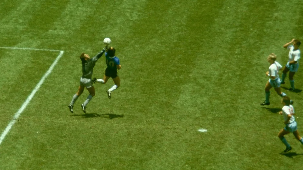 1986 Dünya Kupası'ndaki unutulmaz anlardan biri olan ve Tanrının Eli olarak bilinen olayda, Arjantinli Maradona'nın mavi formasıyla kalecinin üzerinden yükselerek topa eliyle müdahale ettiği o kritik an yeşil sahada diğer oyuncuların da bakışları arasında çekilmiştir.