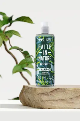 Beyaz bir stüdyo ortamında, doğal görünümlü bir taş kaide üzerinde sergilenen, Faith in Nature markasına ait, üzerinde biberiye yaprağı desenleri ve Rosemary Shampoo yazısı bulunan yeşil kapaklı, şeffaf bir şişe içinde 400 ml vegan saç bakım ürünleri şampuanı görünüyor; bu ürün normal ve yağlı saçlar için dengeleyici formülüyle dikkat çekiyor.