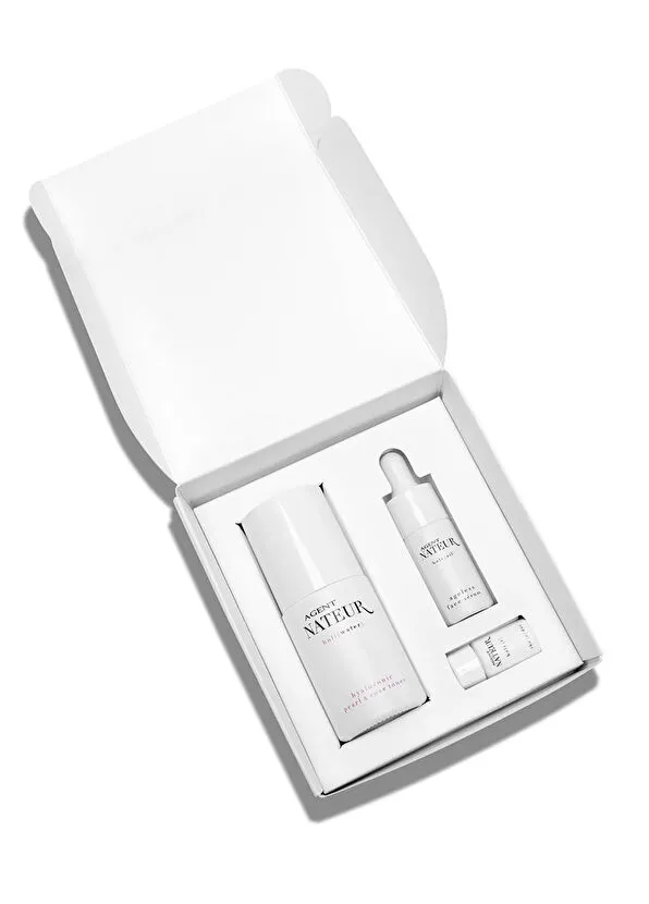Açık beyaz bir kutu içinde Agent Nateur'un Holi Trinity serisinden holiwater toner, ageless face serum ve küçük bir tüp içeren üç adımlı, yatıştırıcı ve besleyici seyahat boyu cilt bakımı seti.