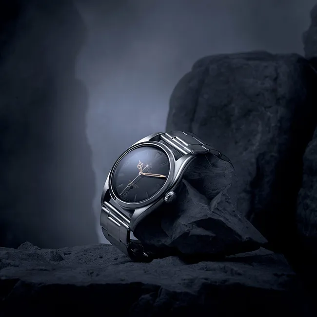 Rolex Oyster Perpetual Explorer; dayanıklılığı ve macera ruhunu yansıtan, kaya üzerinde sergilenen ikonik çelik saat modeli.