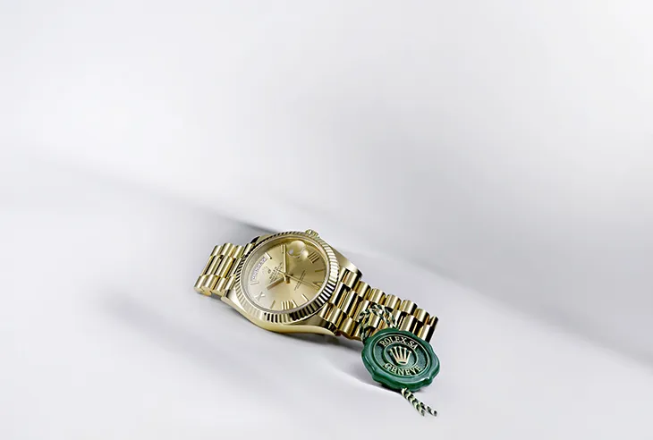 Yeşil ‘Superlative Chronometer Certified’ mührüyle birlikte sergilenen altın Rolex saati; markanın hassasiyet ve kalite standardını simgeliyor.