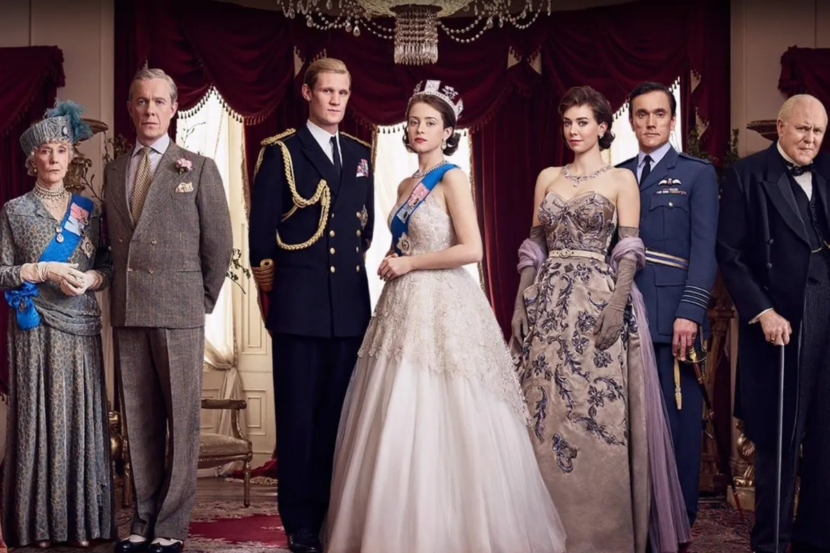 Kraliçe II. Elizabeth (Claire Foy), Prens Philip (Matt Smith) ve Prenses Margaret (Vanessa Kirby) başta olmak üzere The Crown dizisinin yedi ana karakteri, döneme özgü kraliyet kıyafetleri ve nişanlarıyla, kırmızı kadife perdeli ve şamdanlı resmi bir salonda ciddi bir duruş sergiliyor.