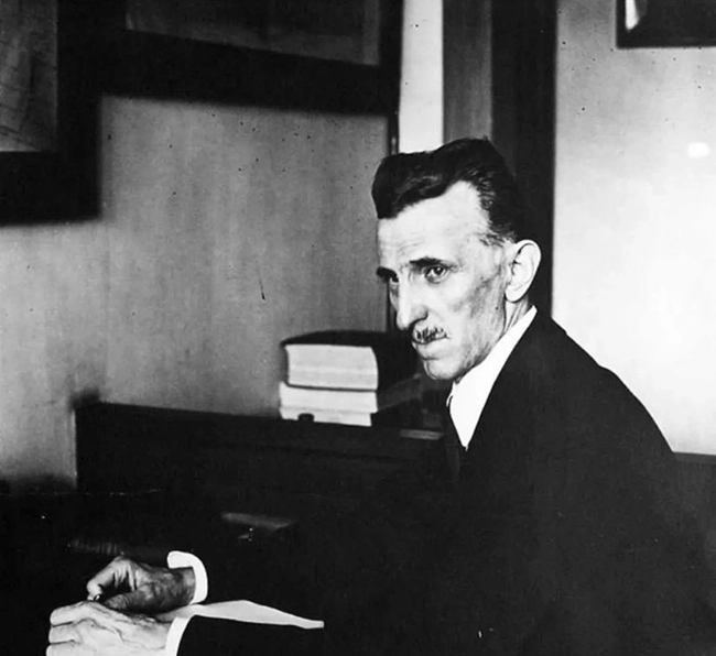 Nikola Tesla’nın hayatının ilerleyen dönemlerinde çekilmiş siyah beyaz bir portresi; masasında otururken düşünceli bakışlarıyla dikkat çeken Tesla