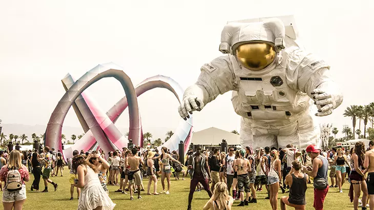 Coachella 2026 festivalinin Indio, Kaliforniya'daki geniş yeşil alanında toplanan coşkulu kalabalık, dev bir astronot heykeli ve iç içe geçmiş renkli sanat enstalasyonları eşliğinde müziğin ve eğlencenin tadını çıkarıyor.