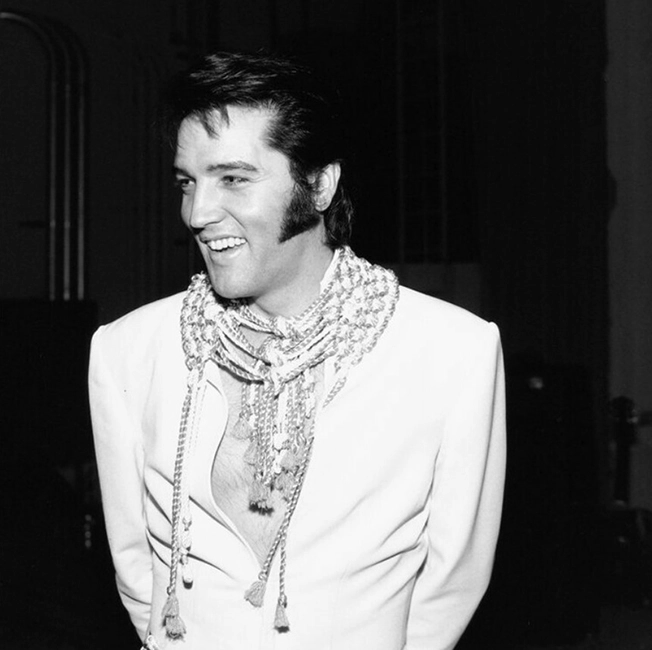 1970’lerde sahne arkasında gülümseyen Elvis Presley, beyaz kostümüyle