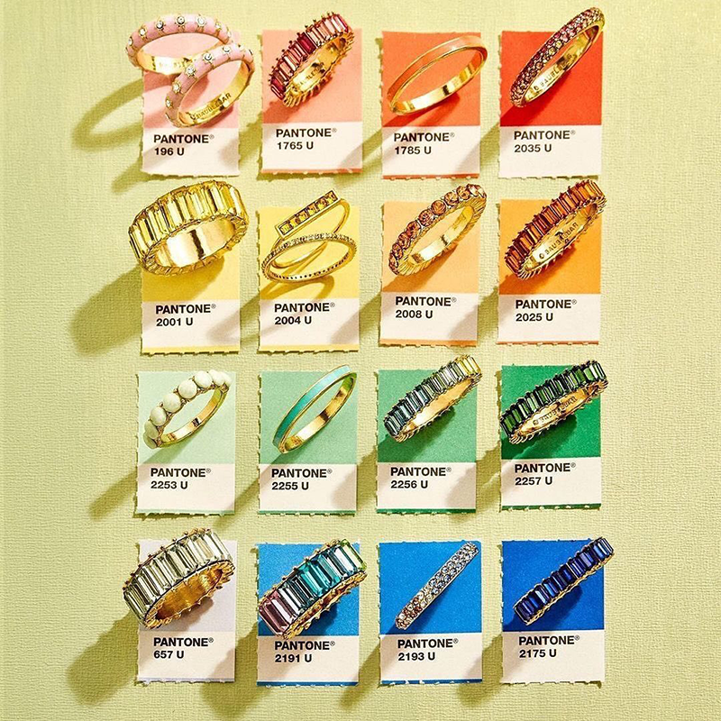 Pantone renk kartelası üzerinde sergilenen altın yüzükler; farklı renk tonlarının takı tasarımlarında nasıl ışık ve stil yarattığını gösteren konsept fotoğraf.