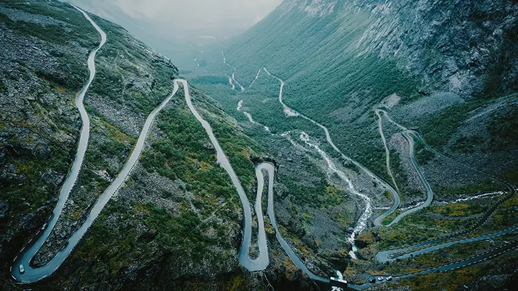 Norveç’teki Trollstigen Yolu üzerinde motosiklet sürerken şelaleler ve dağ manzaraları eşliğinde yüksek rakımlı dağ geçidi