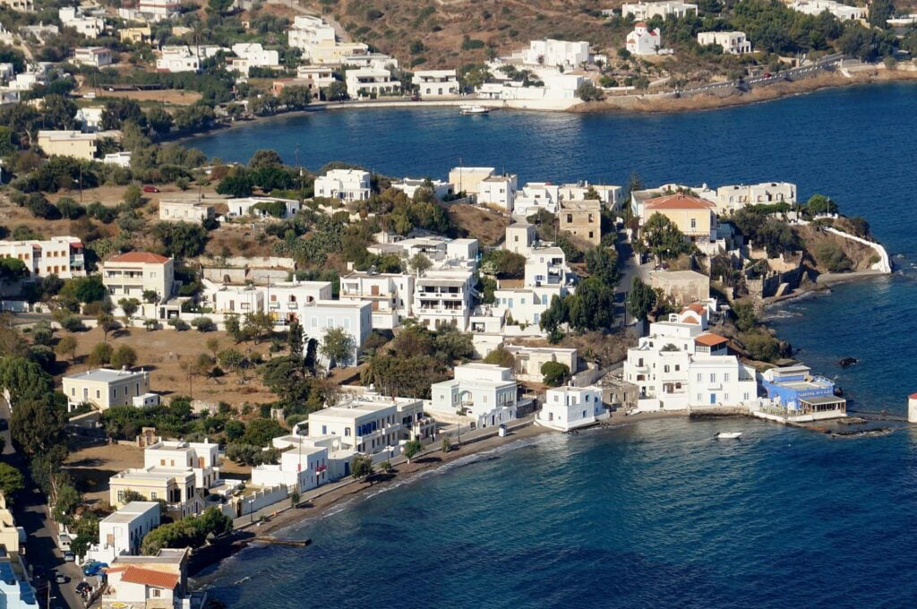 Yunanistan'ın en popüler tatil yerlerinden Leros Adası'nda, tipik beyaz evlerin sıralandığı sakin bir sahil şeridi, berrak masmavi Ege Denizi ve yemyeşil tepelerle çevrili huzurlu bir kıyı kasabası kuşbakışı görünüyor.