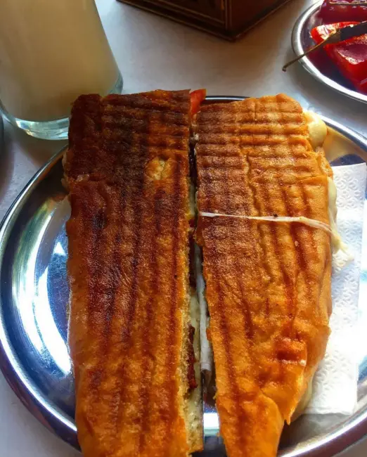 Muğla Akçapınar Tostçusu: yol üstü tost duraklarının efsanesi. Büyük porsiyonlu tost, yanında ayran ve turşuyla servis ediliyor.