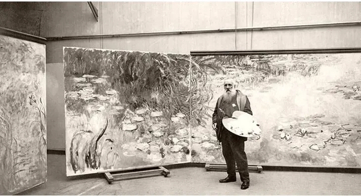 Claude Monet'nin stüdyosunda, büyük boyutlu nilüfer tablolarının önünde paletiyle dururken çekilmiş siyah beyaz bir fotoğrafı.