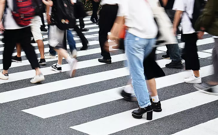 Yoğun bir yaya geçidinde hareket halinde olan insanların bacakları ve bulanık ayakları, şehirde yaşanan hızlı tempoyu vurgulayarak slow living rehberinin ele aldığı modern yaşam koşullarına gönderme yapıyor.