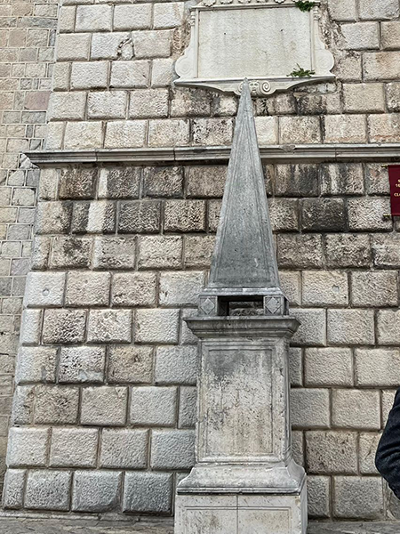 Kotor eski şehirde, yıpranmış taş duvara yaslanan sivri tepeli bu anıt, 17. yüzyıla dek suçluların bileklerinden asıldığı ve Karadağ'ın geçmişteki adalet anlayışını simgeleyen tarihi bir utanç piramididir.